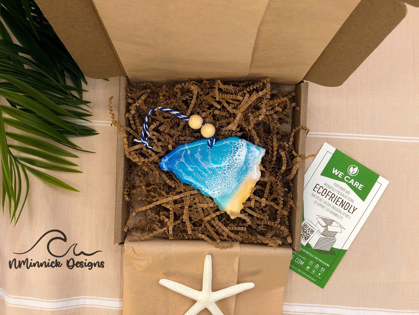 South Carolina Beach Resin ornament laying in an ecofriendly recyclable packing box with kraft colored tissue paper and paper shred