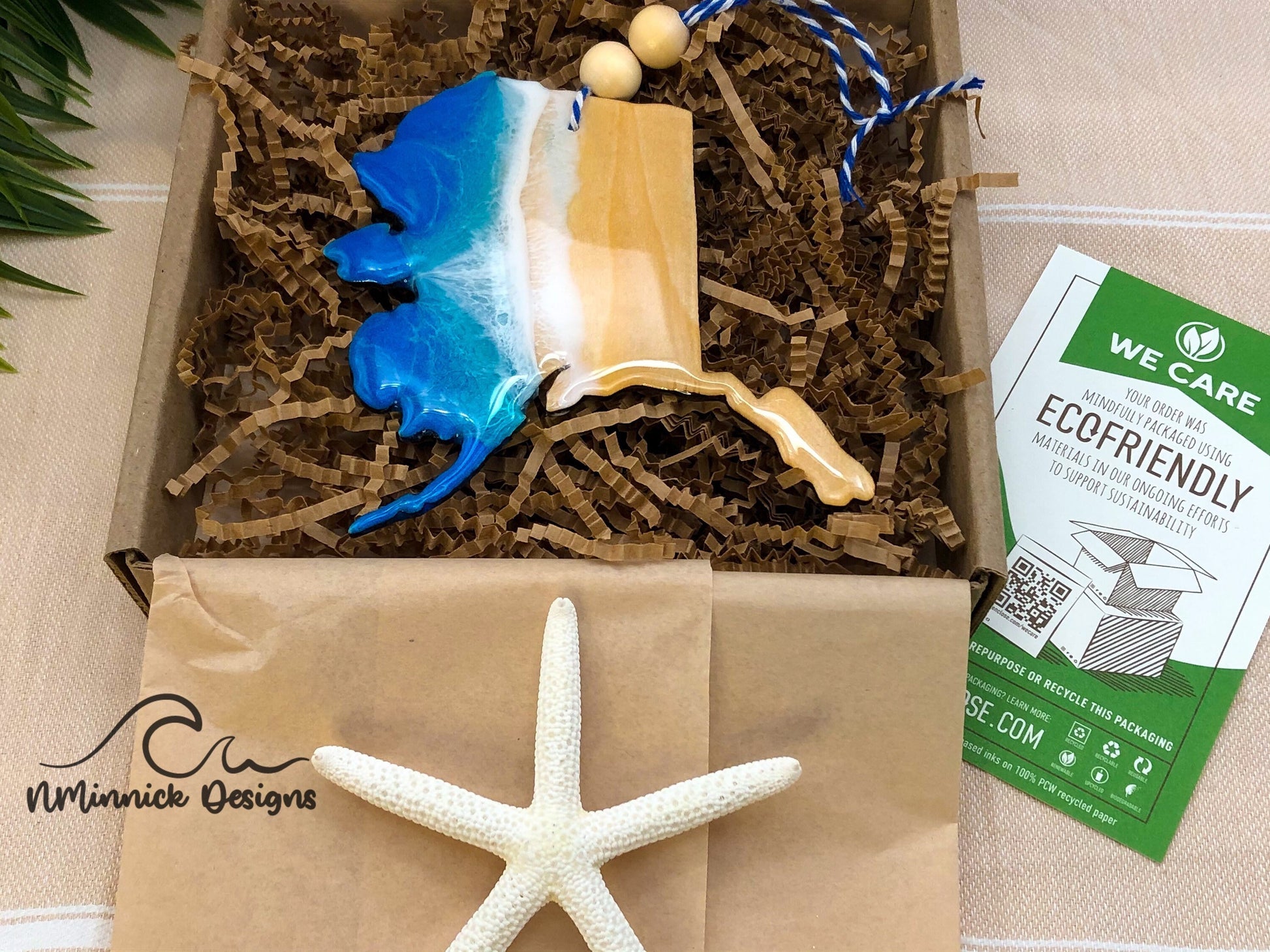 Alaska shaped ocean ornament packaged in ecofriendly plastic free materials with recyclable box, tissue paper and paper shred.