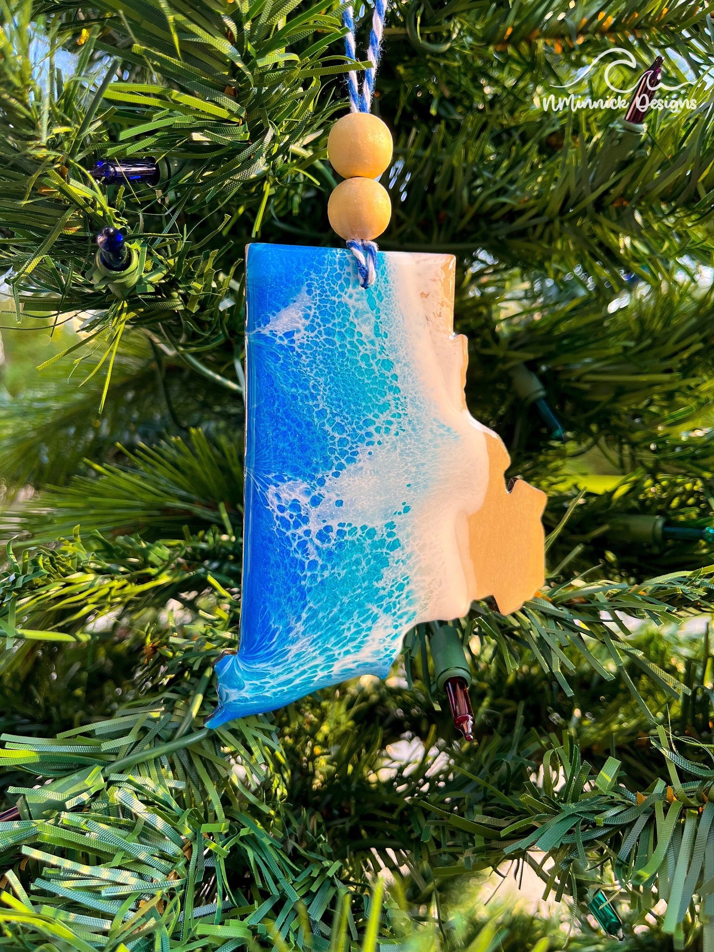 Rhode Island shaped wooden ornament with ocean resin art and hanging from a christmas tree.