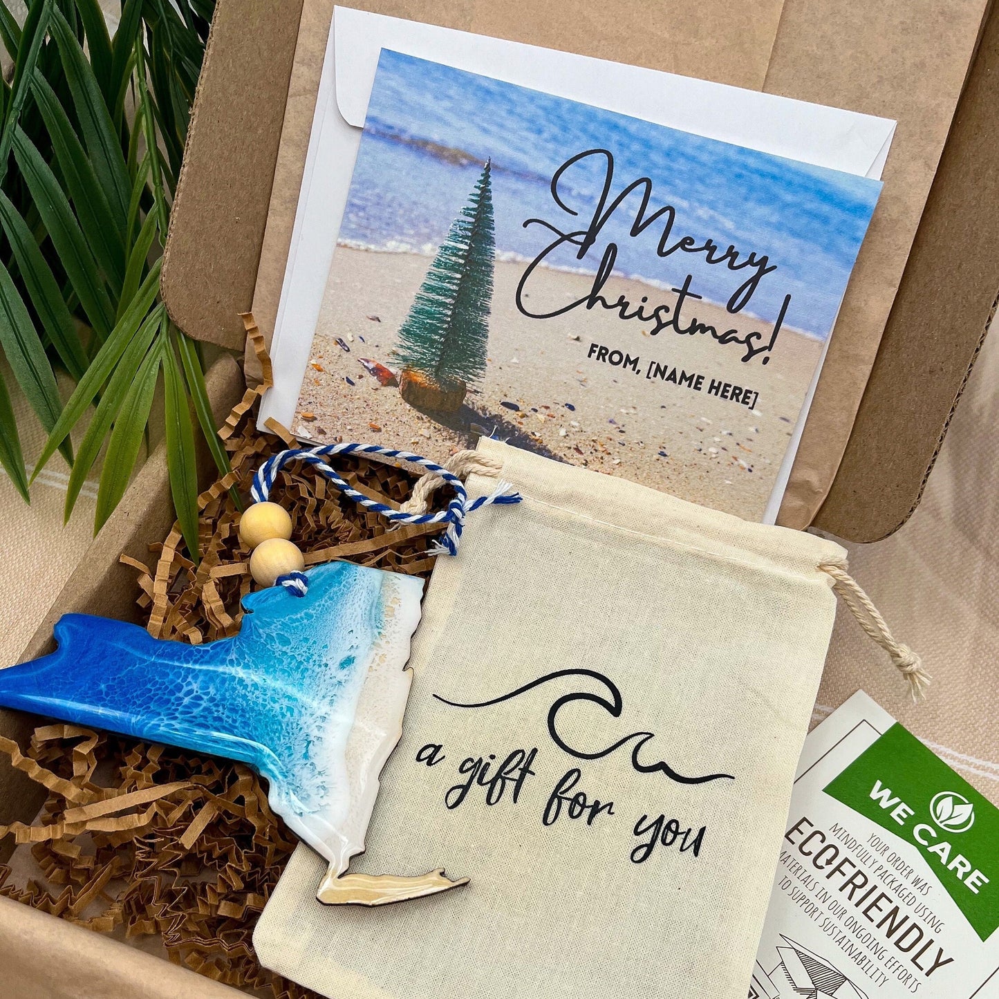 A New York shaped wooden christmas ornament with ocean resin art, resembling the waves of the ocean. In a box with an ornament keepsake bag with a wave that says &quot;a gift for you&quot; and a Merry Christmas custom card.