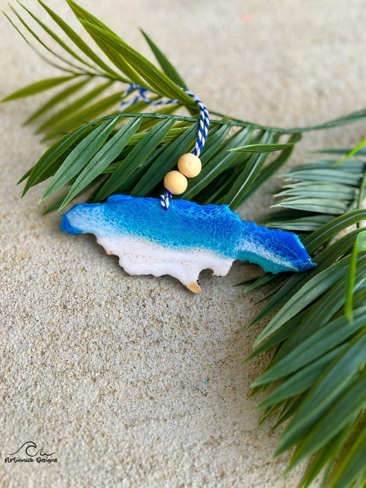 Jamaica Ornament with ocean resin art laying against palm leaves.
