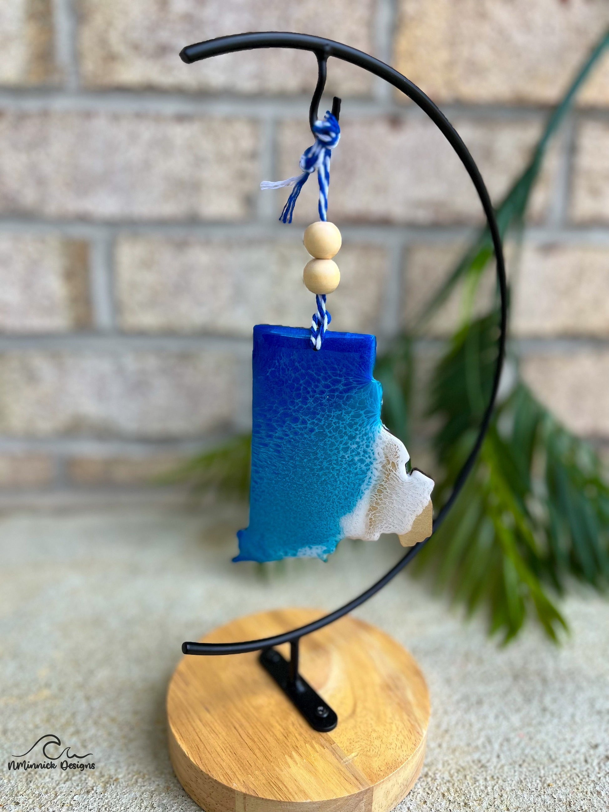 Rhode Island shaped ornament with ocean resin art hanging from an ornament stand.
