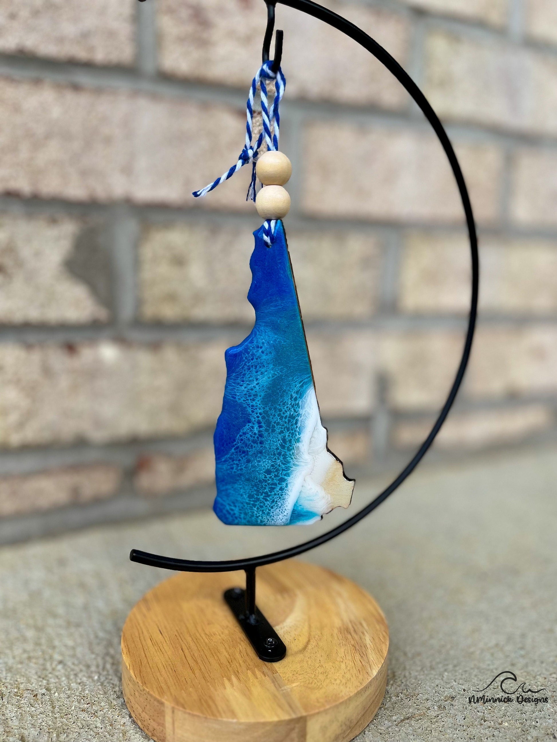 New Hampshire wood and resin ornament made to look like ocean waves. Hanging from an ornament stand.