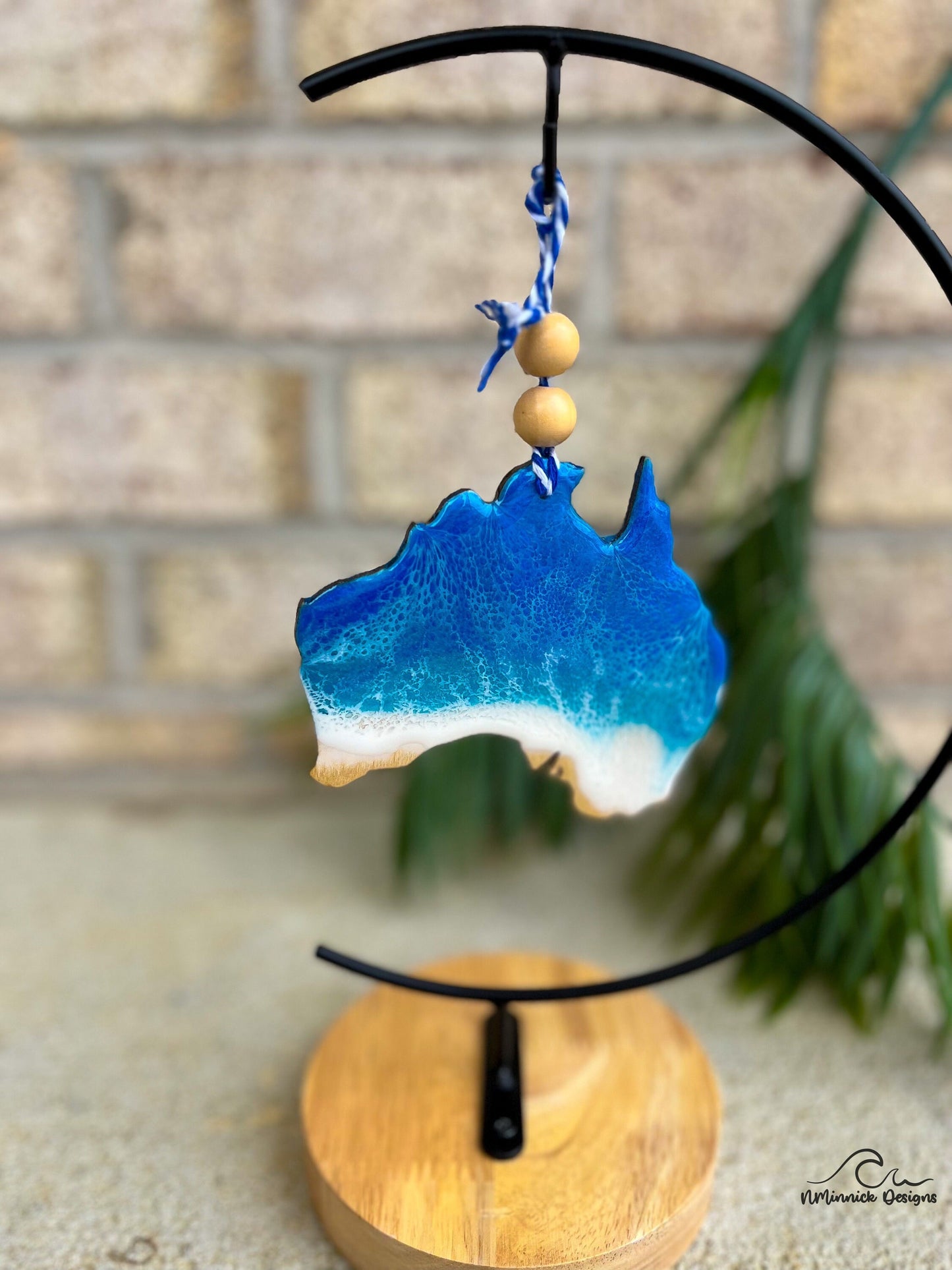 Australia shaped ocean resin ornament hanging on an ornament stand.