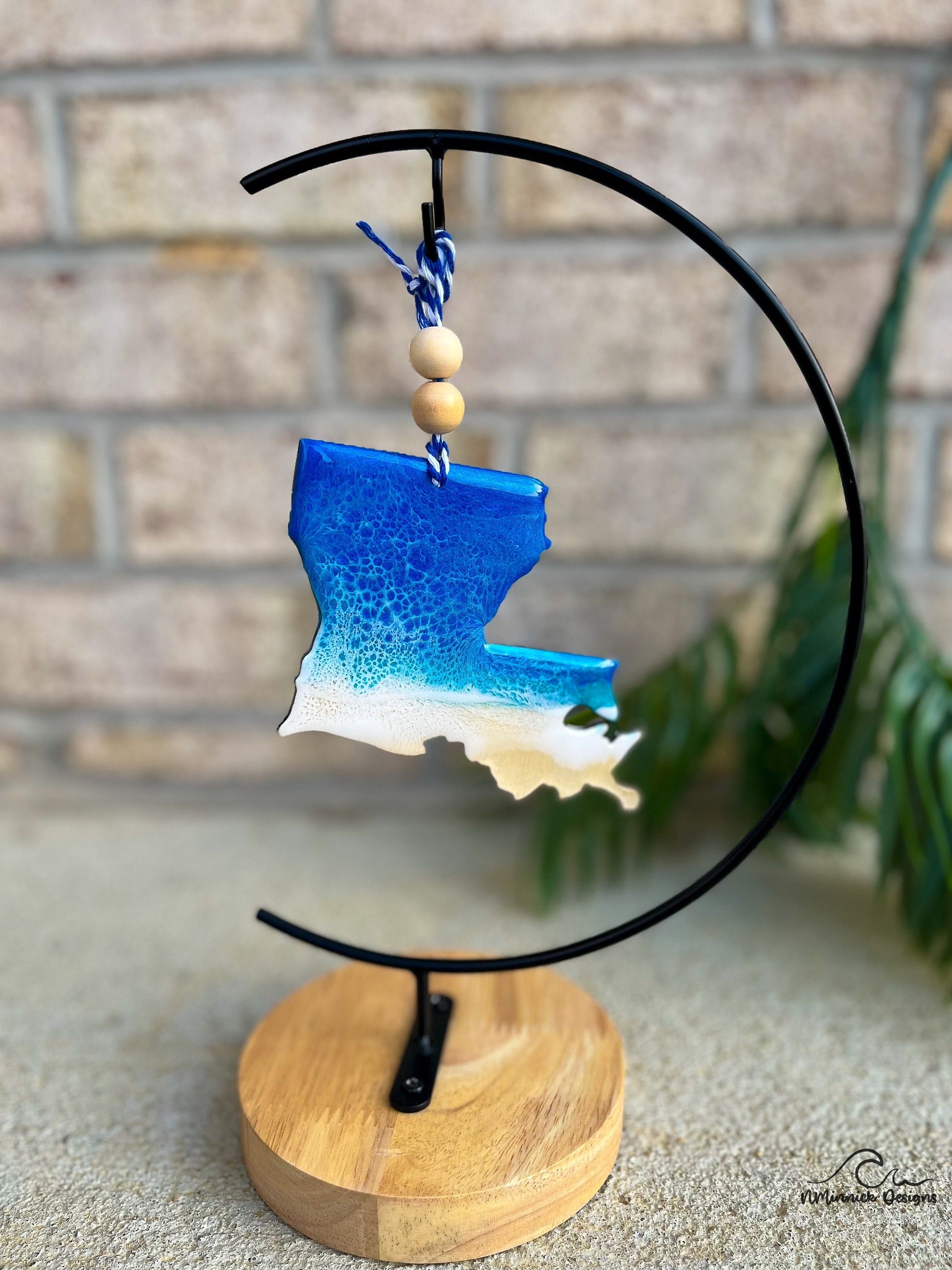 Louisiana coastal ornament with ocean wave art hanging from an ornament stand.