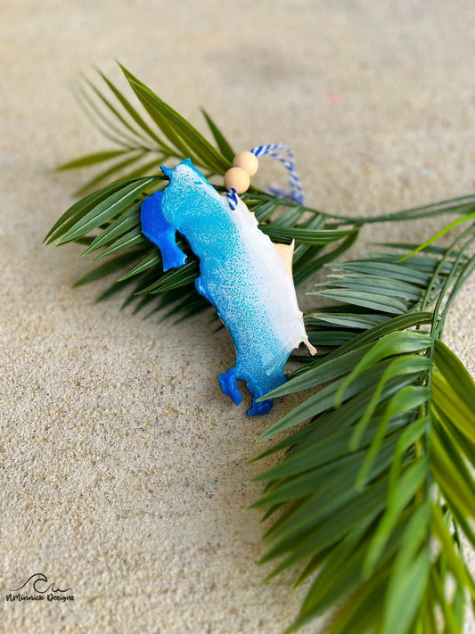 Costa Rica Ornament with Ocean Resin Art laying against palm leaves.