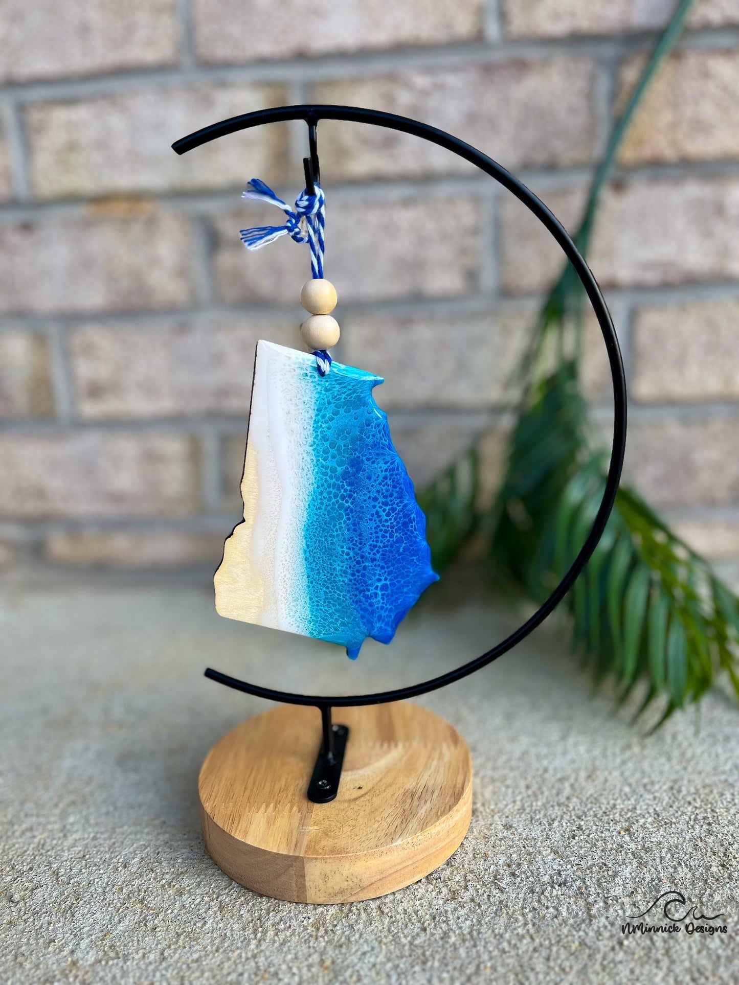 Georgia ornament with ocean resin art hanging from an ornament stand.