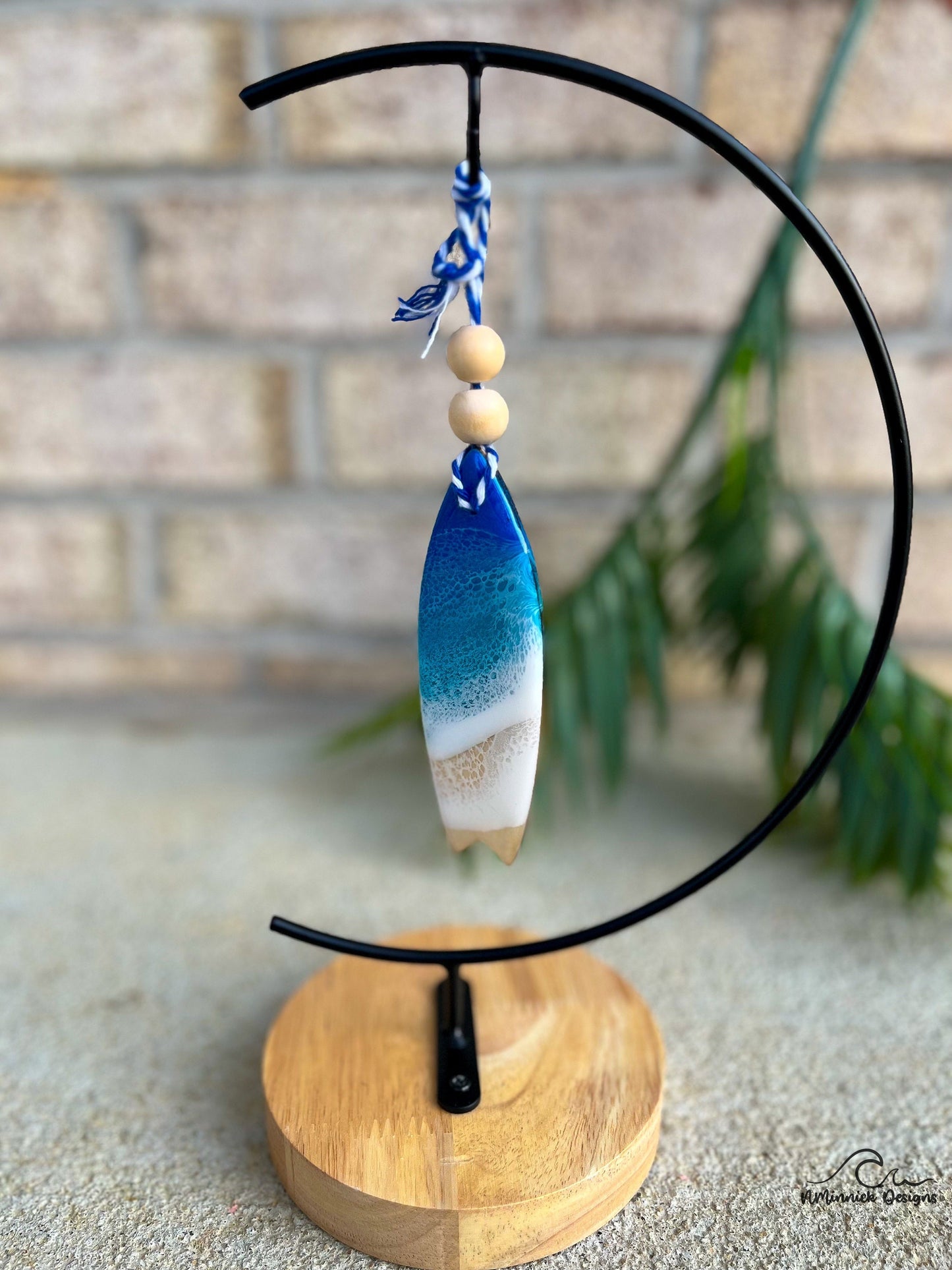 Blue Ocean Surfboard shaped ornament hanging from an ornament stand.