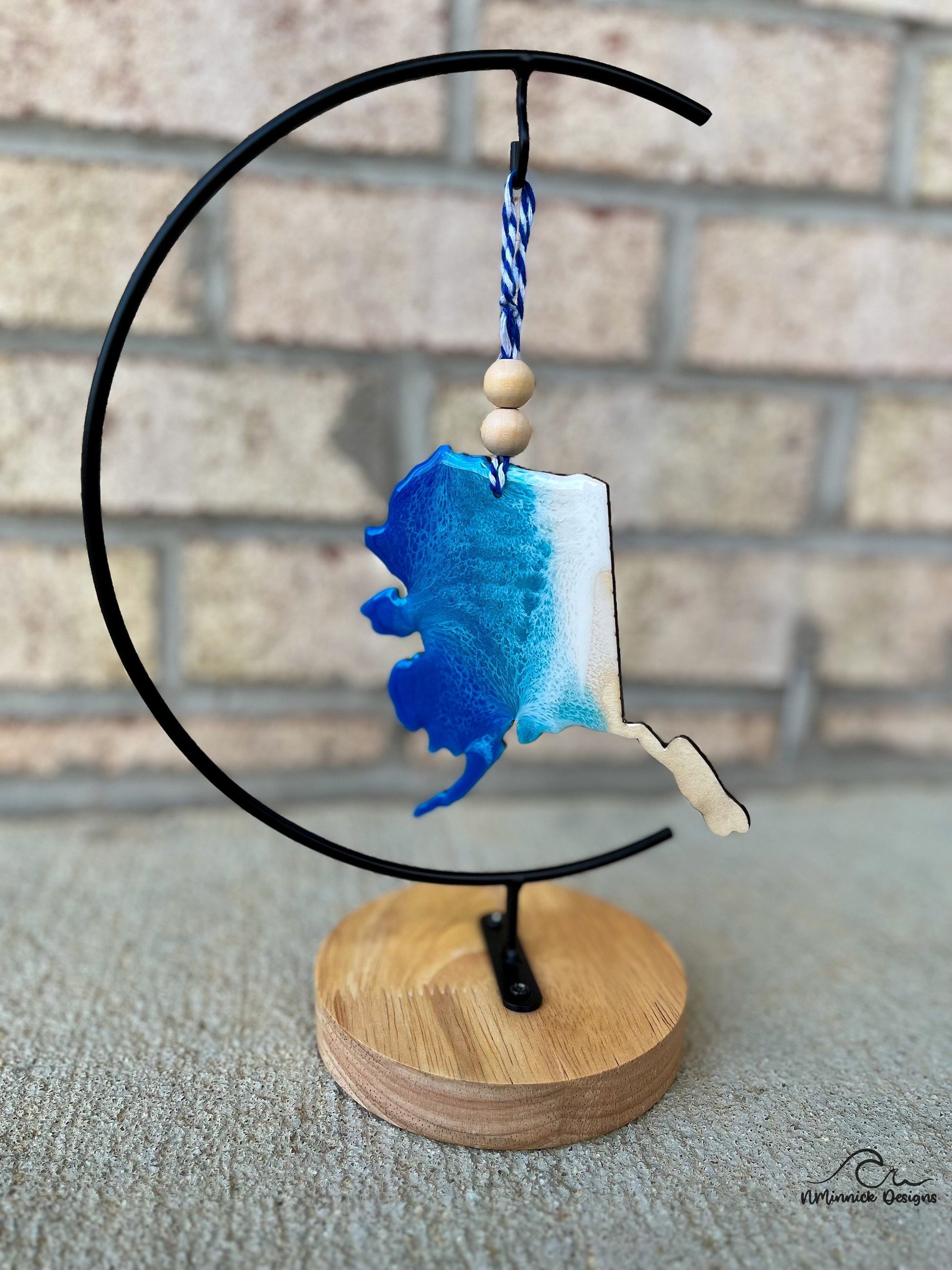 Alaska Coastal Ornament with ocean resin art hanging from an ornament stand.