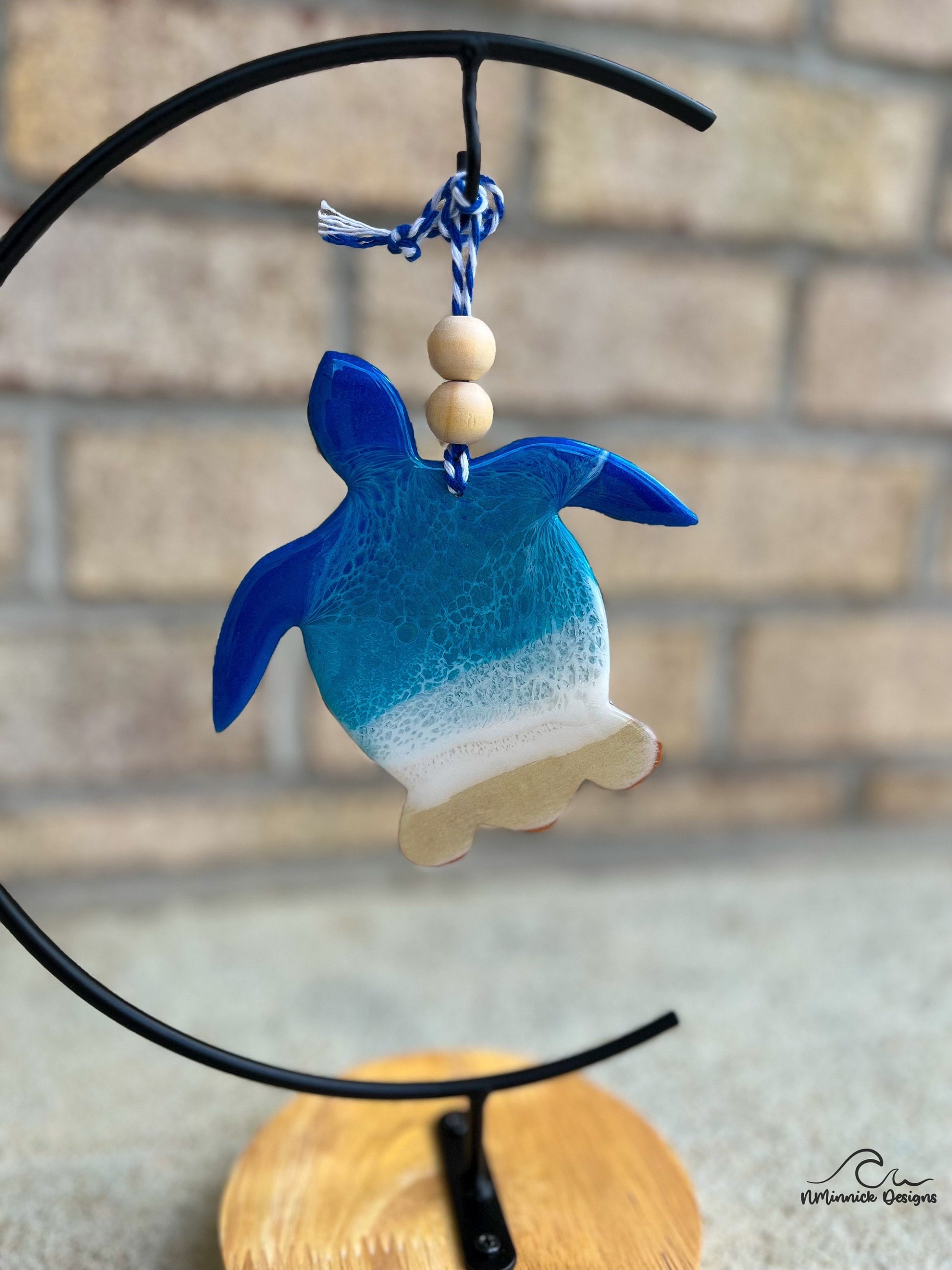 Sea Turtle shaped wood and resin ornament with ocean resin art hanging from an ornament stand.