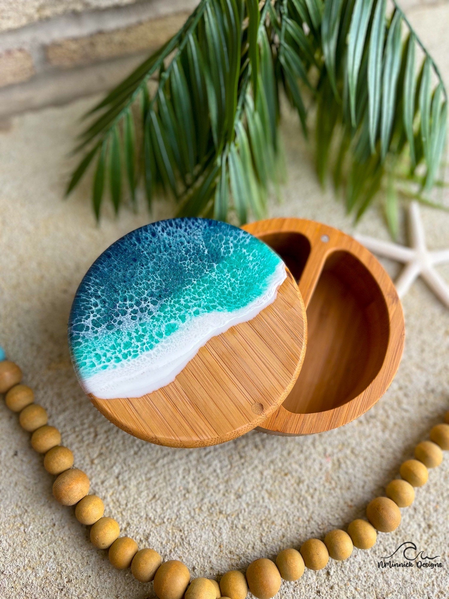 Dual salt and pepper bamboo spice storage cellar with dark blue and green ocean resin art on the top and a magnetic closure.