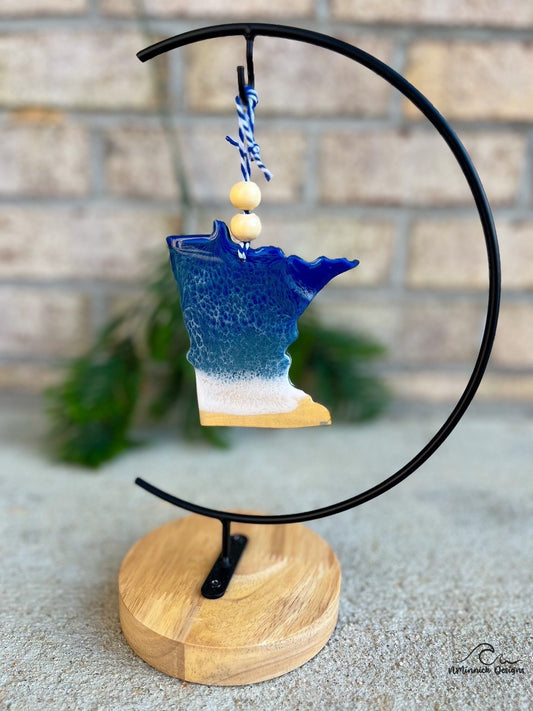 Minnesota shaped laser cut wood ornament adorned with dark blue and grey blue resin waves inspired by the great lakes