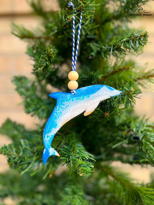 dolphin shaped wooden ornament with one side coated in blue ocean resin wave art and hanging on a Christmas tree