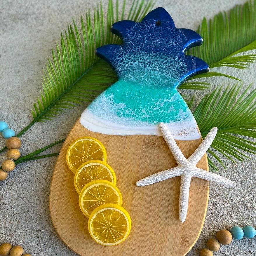 Pineapple shaped bamboo cutting board with dark blue and teal ocean resin art on the top