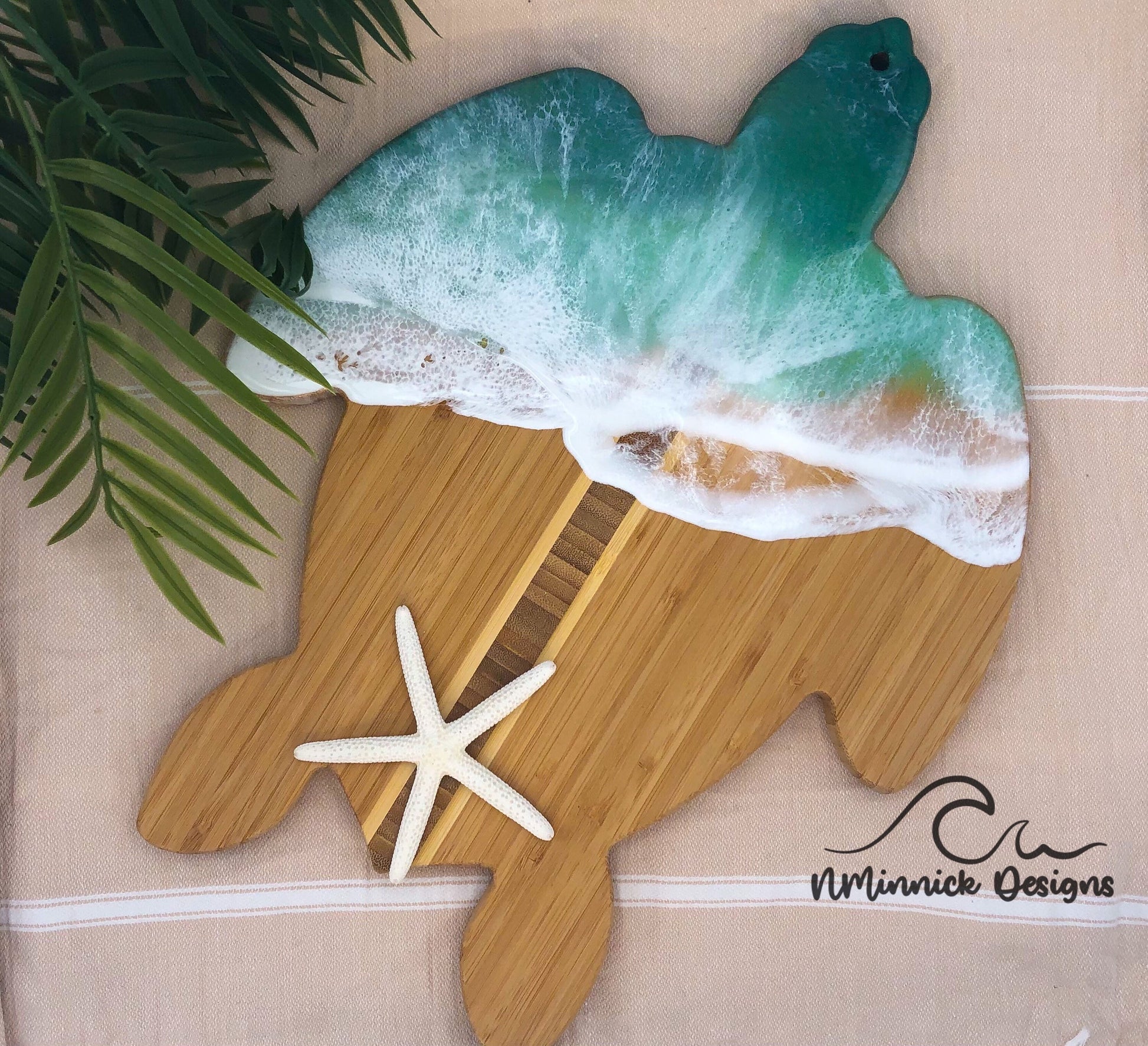 sea turtle shaped bamboo charcuterie board with an epoxy resin ocean in dark green and light green covering the top third of the board.
