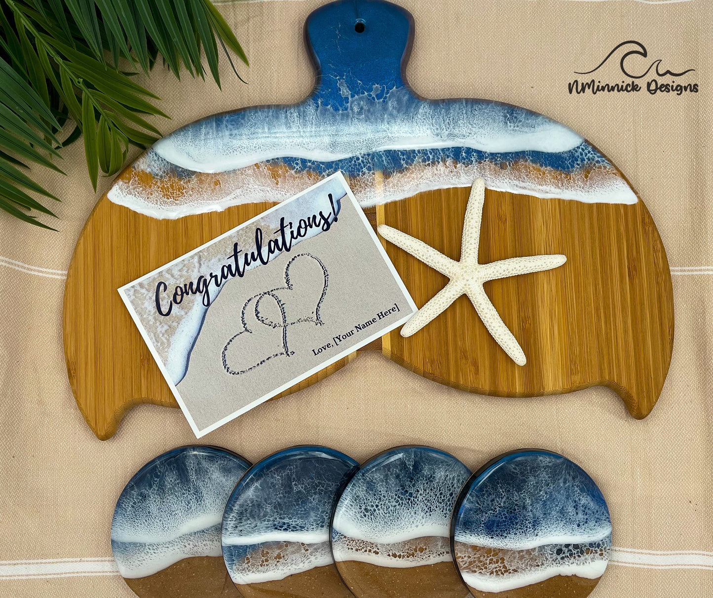 Whale Fin-shaped bamboo charcuterie board with top portion covered in dark and medium blue ocean resin art resembling the waves of the ocean. Matching set of 4 ocean resin drink coasters with cork backing and a free personalized Congratulations Card.