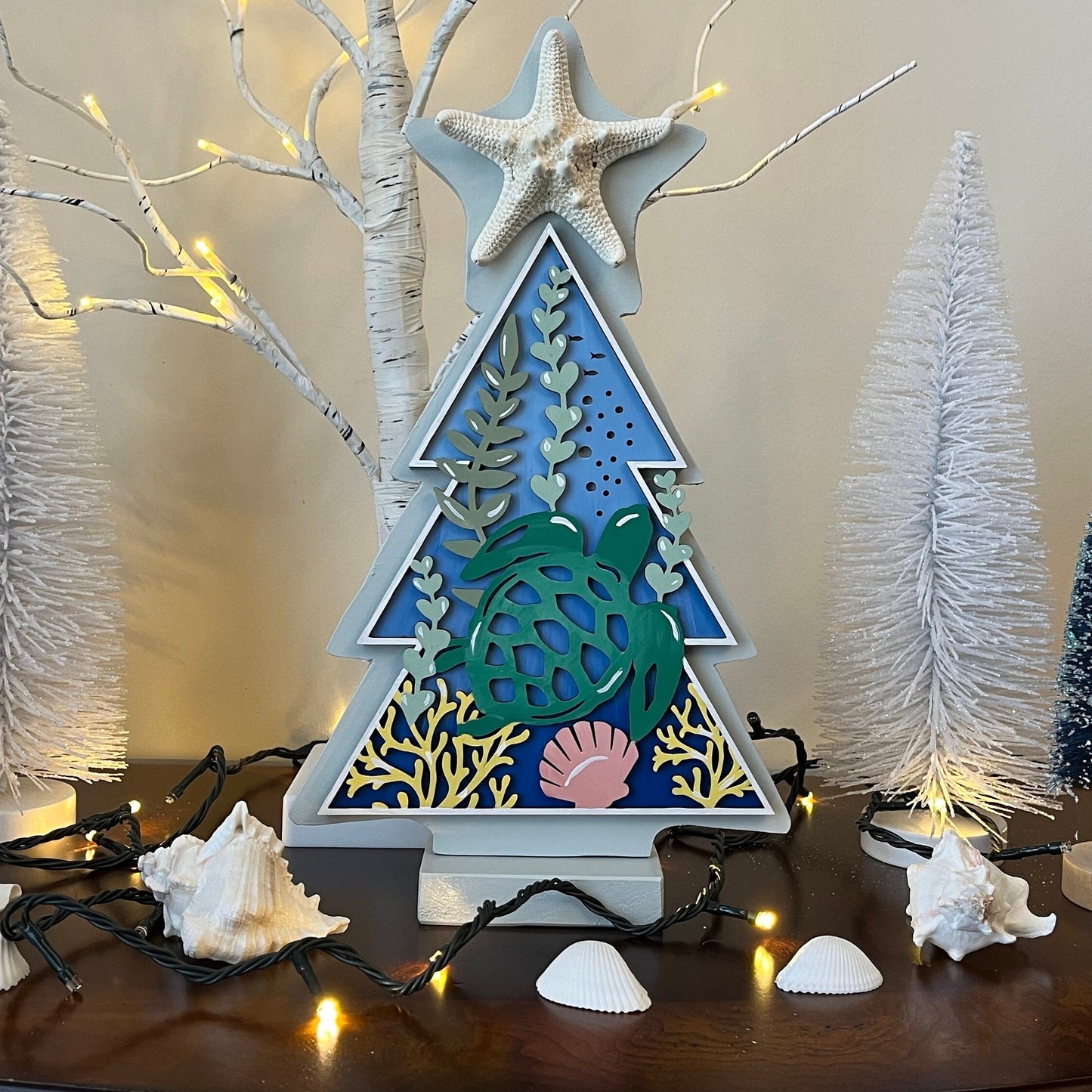 A 12-inch tall wooden standing tree shaped decor with a starfish on top and a sea turtle under the sea hand painted scene on the center.